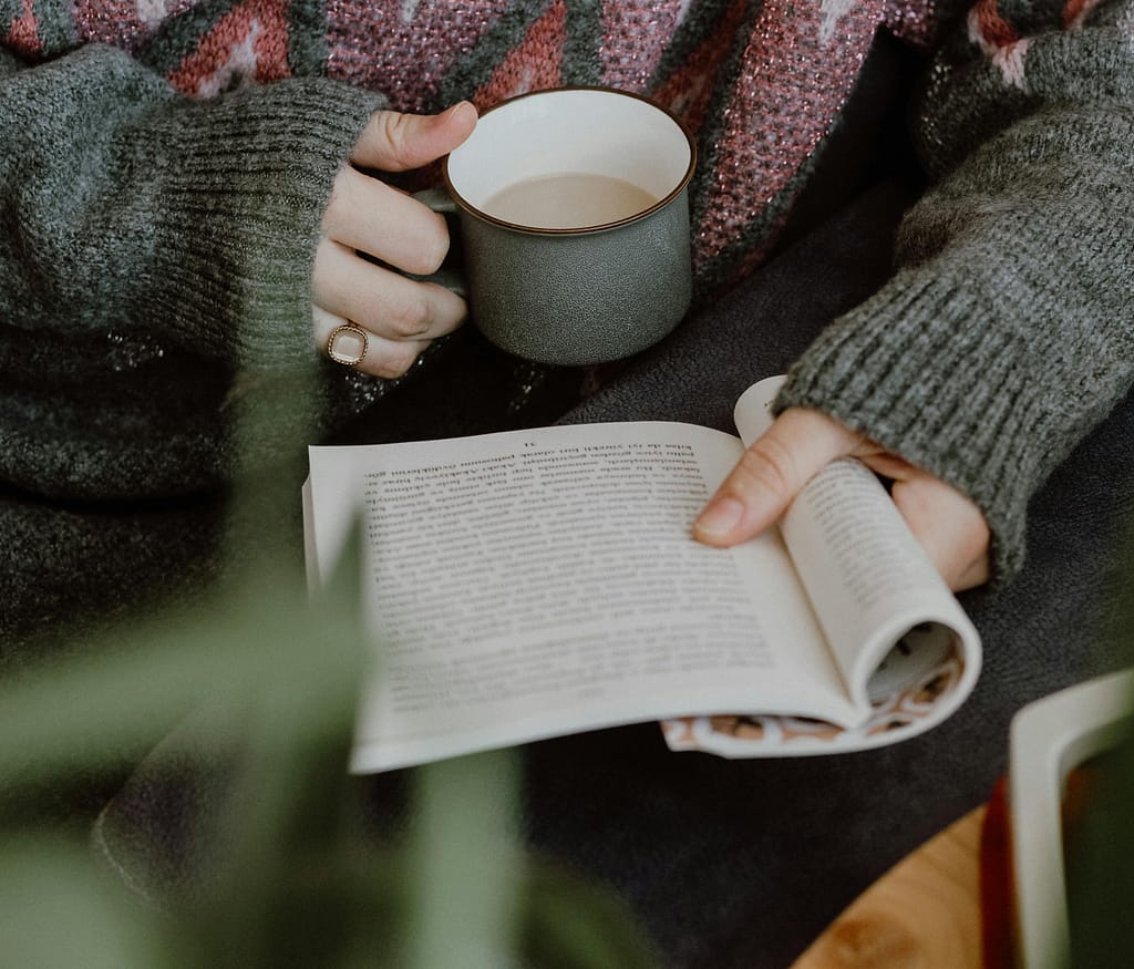 Holiday Reading  - a person holding a book and a mug